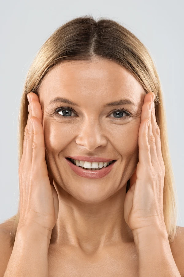 woman holding her hands to her face happy with Blepharoplasty results